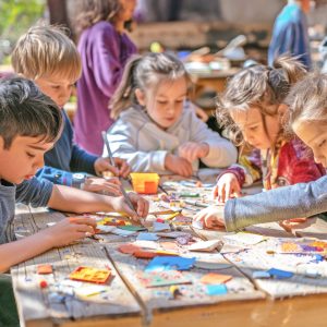 Top view of kids engaging in outdoor arts and crafts, creating nature-inspired projects at a wooden table. AIG53M